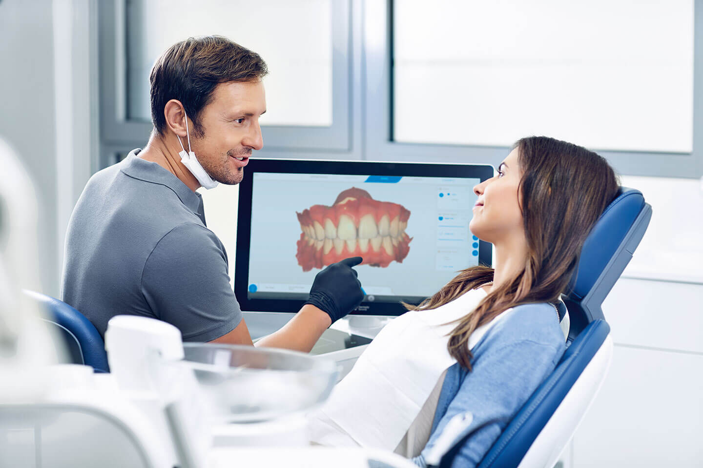 Zahnarzt mit Patienten vor CEREC-Monitor in Besprechung
